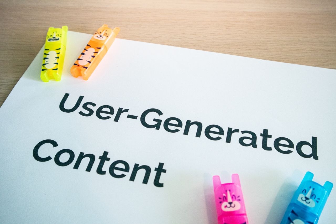 Bright neon markers on a User-Generated Content note placed on a wooden desk.